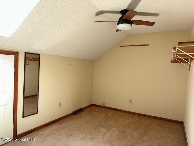 interior space with visible vents, a ceiling fan, vaulted ceiling, and light carpet