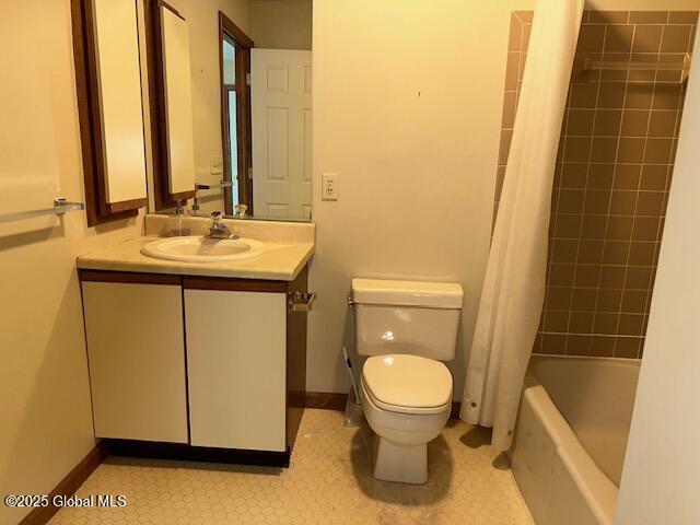 bathroom featuring vanity, baseboards, shower / bath combo with shower curtain, and toilet
