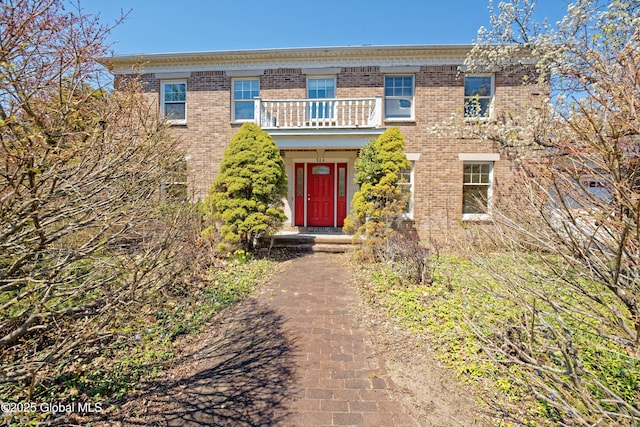 view of front facade featuring brick siding and a balcony