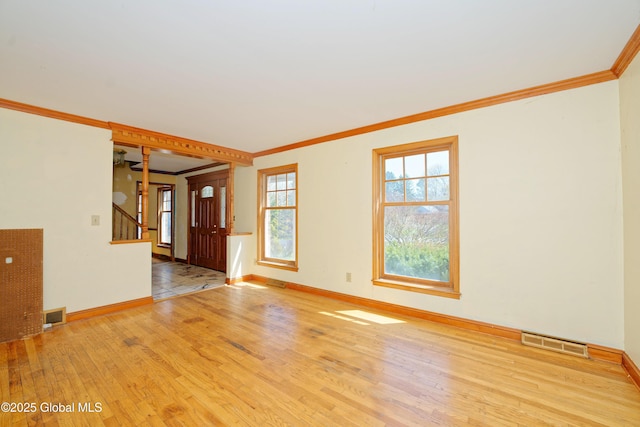 spare room with crown molding, baseboards, wood finished floors, and visible vents