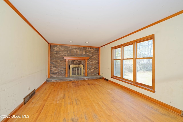 unfurnished living room featuring crown molding, a fireplace, light wood-type flooring, and visible vents