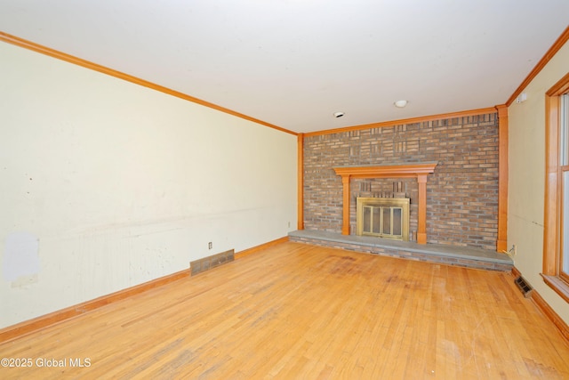 unfurnished living room with crown molding, a fireplace, wood finished floors, and visible vents