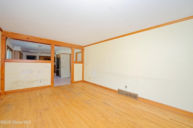 unfurnished room with visible vents, baseboards, hardwood / wood-style flooring, and decorative columns