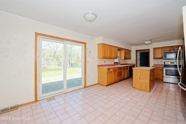 kitchen with visible vents, a kitchen island, light countertops, a sink, and black appliances