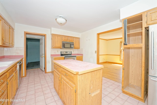 kitchen with decorative backsplash, a kitchen island, light countertops, appliances with stainless steel finishes, and light tile patterned floors