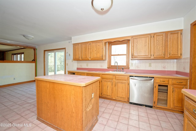 kitchen featuring backsplash, a center island, dishwasher, a sink, and light countertops