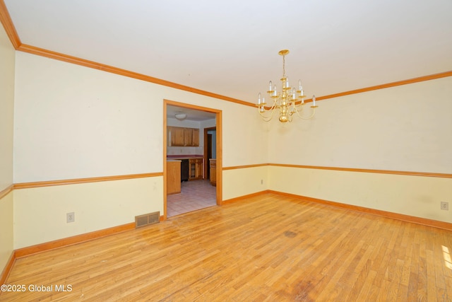 empty room featuring baseboards, a notable chandelier, visible vents, and wood finished floors