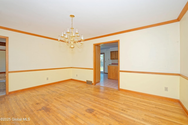 empty room with ornamental molding, wood finished floors, and a notable chandelier