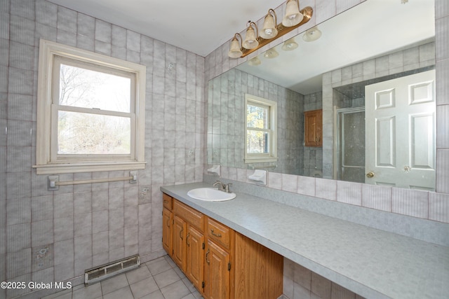 bathroom with visible vents, tile walls, a stall shower, vanity, and tile patterned floors