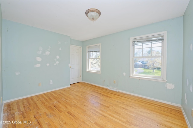 empty room featuring baseboards, visible vents, and light wood-type flooring