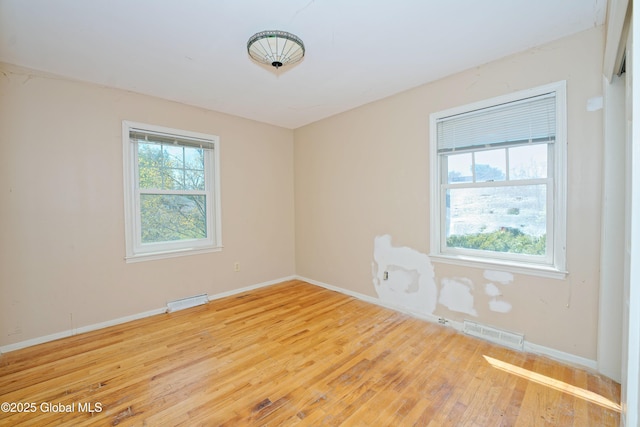 spare room with baseboards, hardwood / wood-style flooring, and visible vents