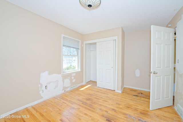 unfurnished bedroom featuring light wood-style floors, baseboards, a closet, and visible vents