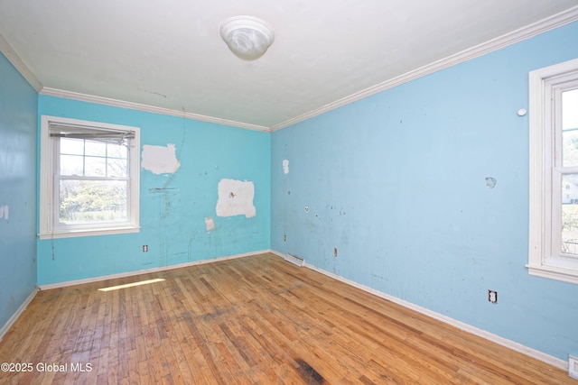 unfurnished room featuring wood-type flooring, crown molding, visible vents, and baseboards