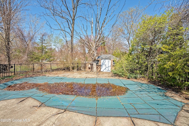 view of swimming pool featuring a storage unit, a fenced backyard, a fenced in pool, an outbuilding, and a patio