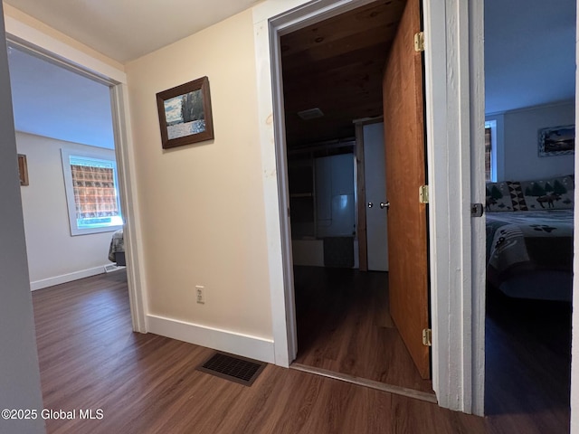 corridor featuring baseboards, visible vents, and wood finished floors