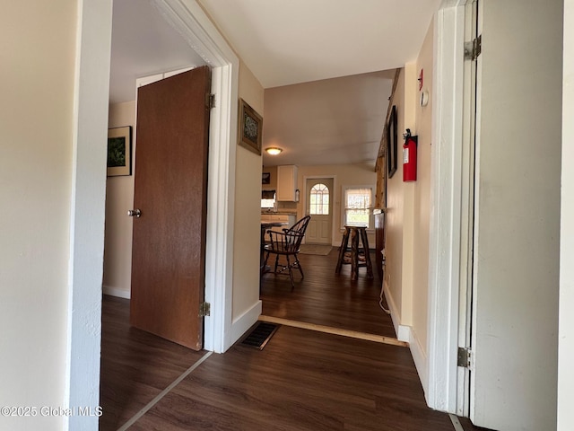 corridor with wood finished floors, visible vents, and baseboards