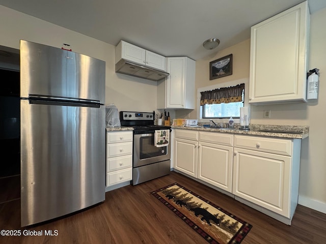 kitchen featuring white cabinets, stainless steel appliances, under cabinet range hood, light stone countertops, and dark wood-type flooring