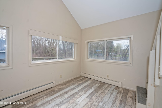 empty room with baseboard heating, vaulted ceiling, wood finished floors, and baseboards