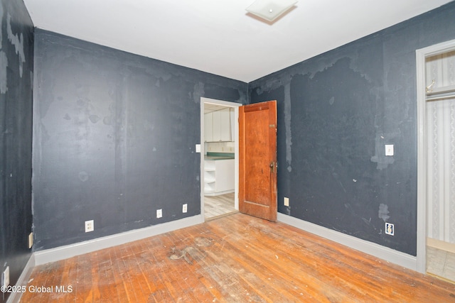 empty room with baseboards and hardwood / wood-style flooring