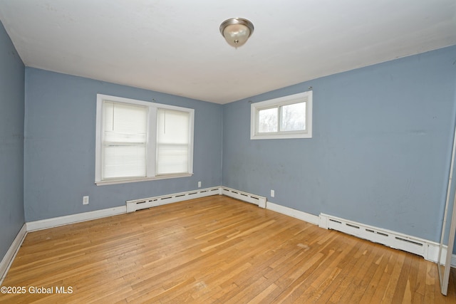 spare room with baseboards, a baseboard heating unit, and light wood finished floors