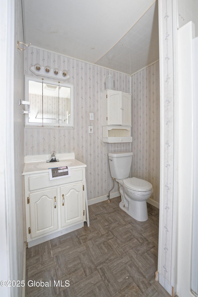 half bathroom featuring toilet, vanity, and baseboards