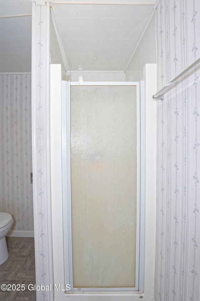 full bathroom featuring ornamental molding, a shower stall, and wallpapered walls