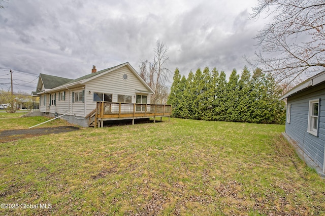 rear view of property with a chimney, a yard, and a wooden deck
