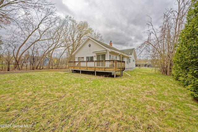 rear view of house with a wooden deck, a yard, and a chimney
