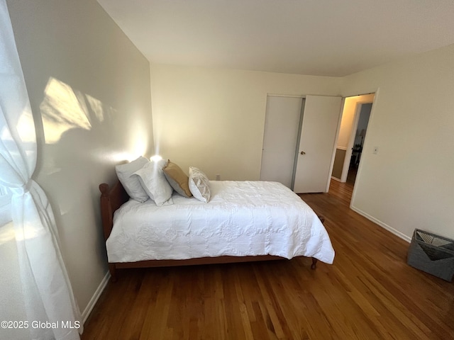 bedroom featuring baseboards, wood finished floors, and a closet