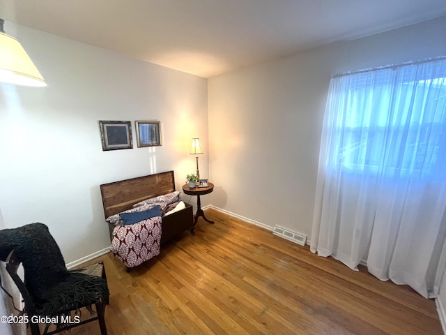 sitting room with baseboards, visible vents, and wood finished floors