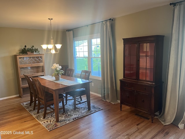 dining room featuring baseboards, a notable chandelier, wood finished floors, and visible vents