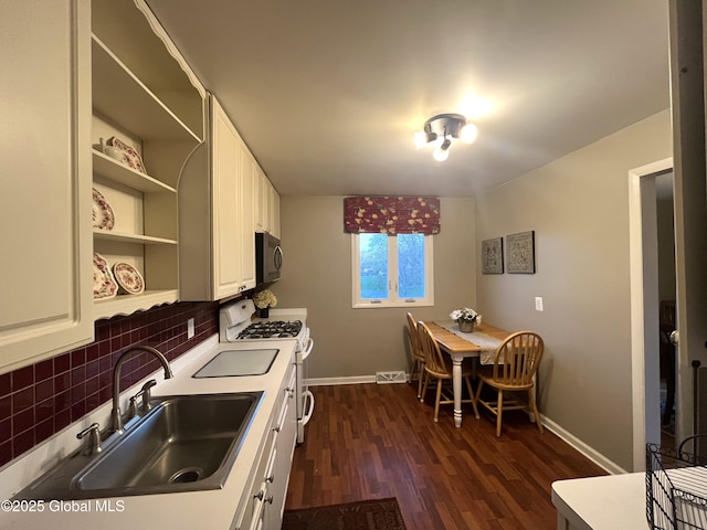 kitchen with tasteful backsplash, open shelves, gas range gas stove, a sink, and baseboards