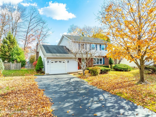 colonial home with driveway, fence, and an attached garage