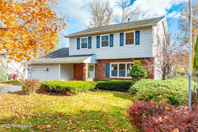 traditional-style house featuring a front yard, an attached garage, and brick siding