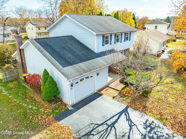 view of property exterior featuring fence, aphalt driveway, a shingled roof, a garage, and a residential view