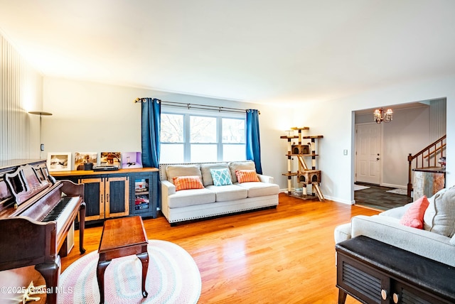 living area with an inviting chandelier, wood finished floors, and stairs