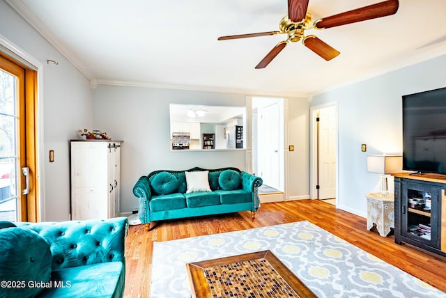 living room with wood finished floors, a ceiling fan, ornamental molding, and baseboards