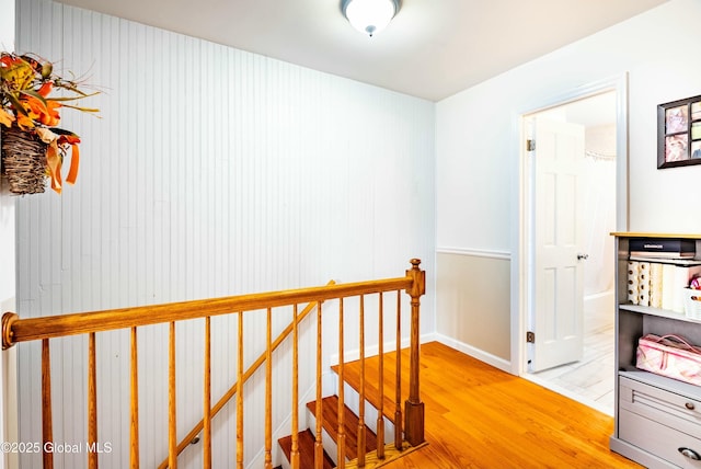 hallway featuring an upstairs landing, baseboards, and light wood-type flooring