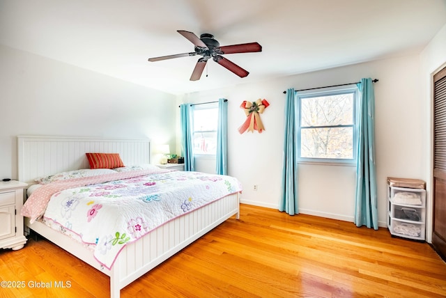 bedroom with ceiling fan, baseboards, and light wood-style floors