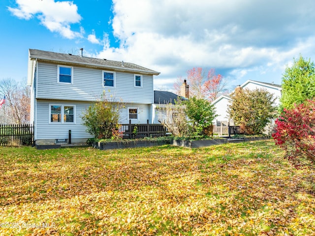rear view of property featuring a lawn, a wooden deck, and fence