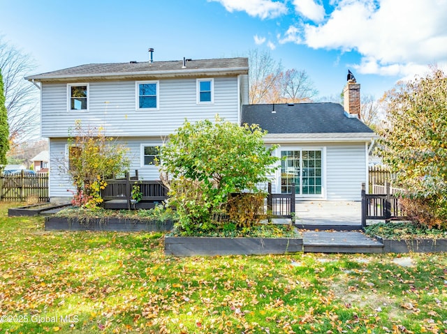 rear view of property with fence, a chimney, a yard, and a wooden deck