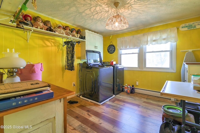 laundry area featuring wood-type flooring, a textured ceiling, baseboard heating, and washing machine and clothes dryer