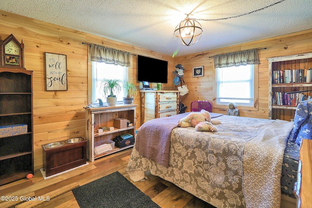bedroom with multiple windows, wood walls, and a textured ceiling