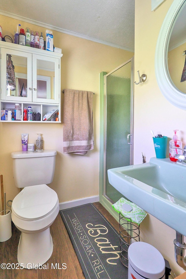 full bathroom with crown molding, a shower stall, wood finished floors, baseboards, and toilet