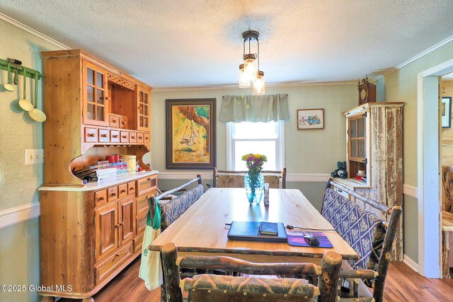 dining space featuring crown molding, a textured ceiling, and wood finished floors