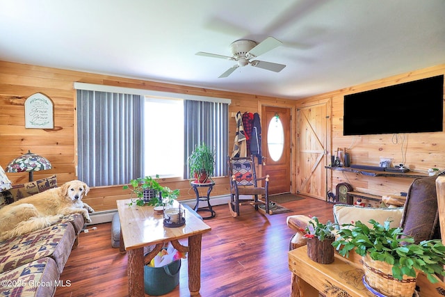 living room featuring wood walls, ceiling fan, wood finished floors, and baseboard heating