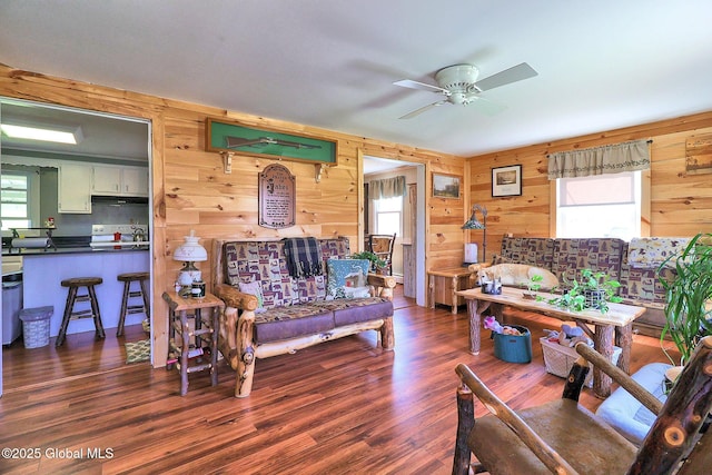living area with ceiling fan, dark wood-style flooring, and wood walls