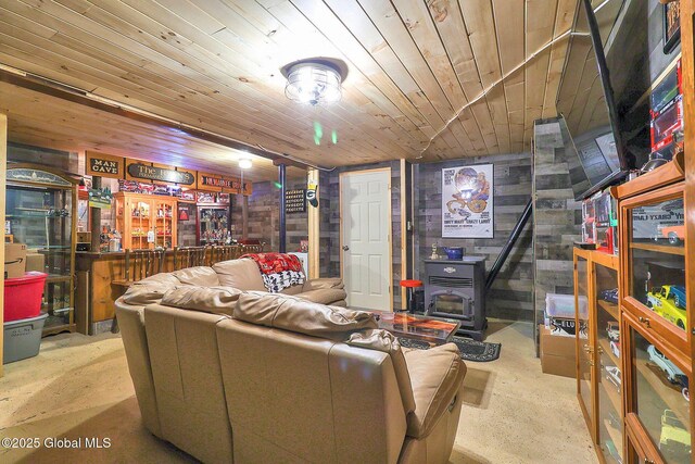 living room with wood ceiling, a dry bar, a wood stove, and concrete flooring