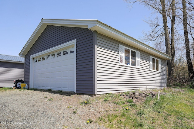 view of property exterior featuring an outbuilding, metal roof, and a garage