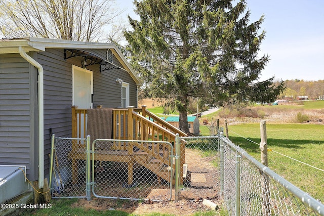 wooden terrace featuring a yard, a gate, and a fenced backyard